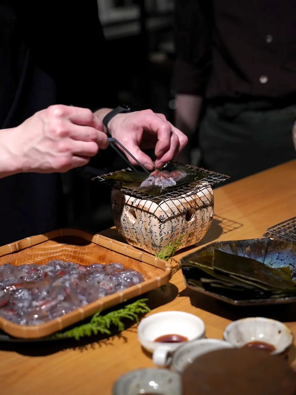 卓上の小さな炭火で炙りを仕上げる料理人の手元